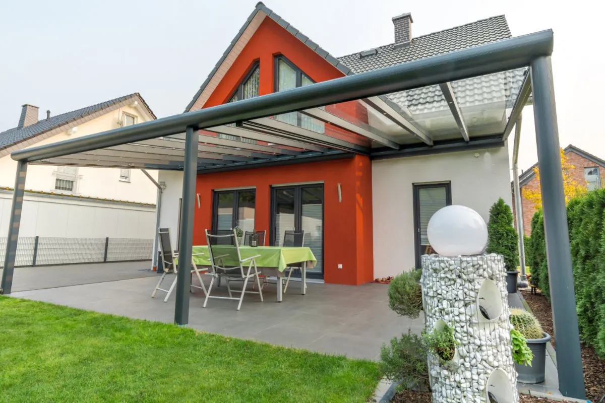Großzügige Terrassenüberdachung aus Aluminium und Glas an einem Wohnhaus mit Garten
